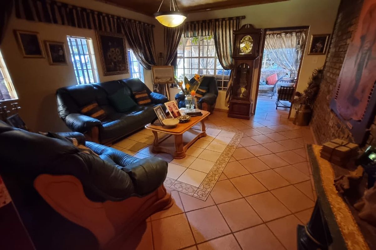 A cozy living room featuring terracotta floor tiles, a rustic exposed brick wall, and a timber-paneled ceiling, with direct access to an outdoor patio area.