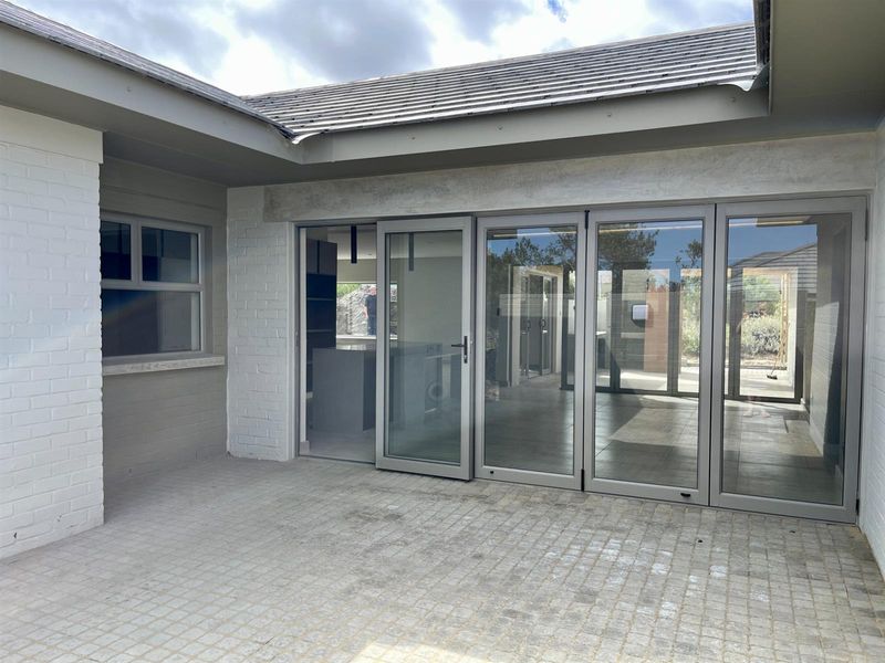 A paved outdoor patio area featuring modern bi-fold glass doors providing seamless access to the interior living space.