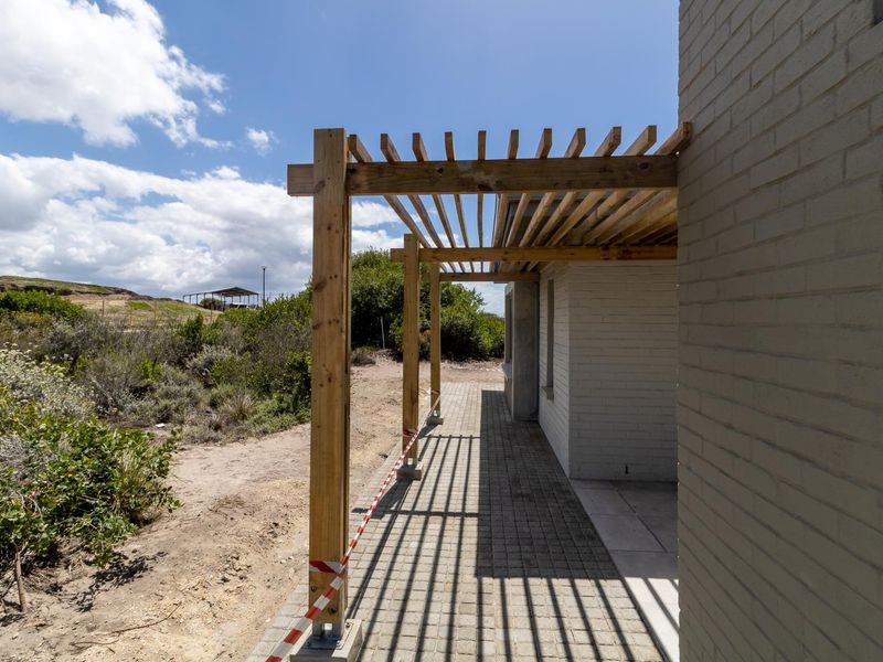 An outdoor patio area featuring a newly installed timber pergola and paved flooring, currently undergoing final finishing touches.
