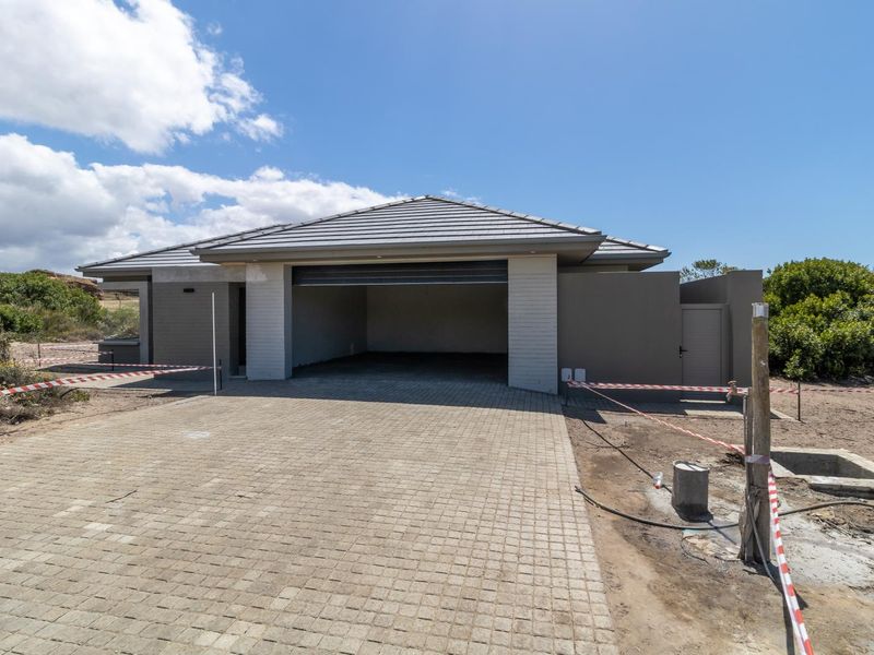 A modern detached garage with a tiled roof and paved driveway, currently situated on a property undergoing final landscaping and site completion.
