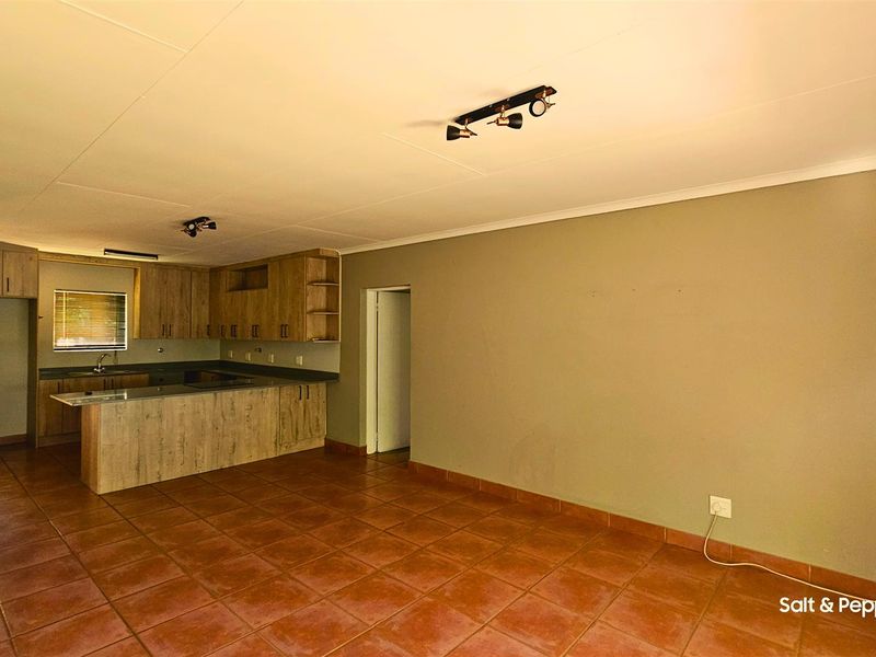 Spacious open-plan living area featuring tiled flooring and a functional kitchen with built-in cabinetry and a central island.