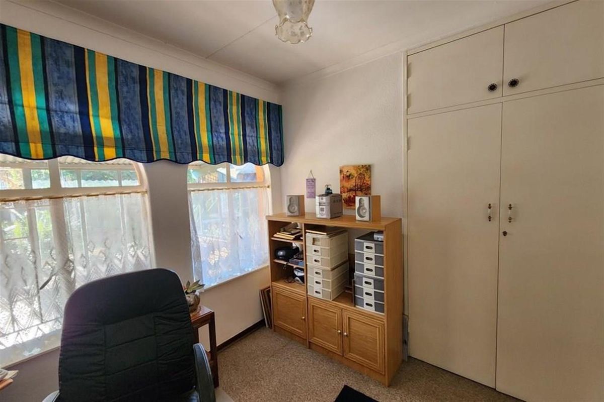 A functional bedroom featuring built-in cupboards and large windows, providing ample natural light and storage space.