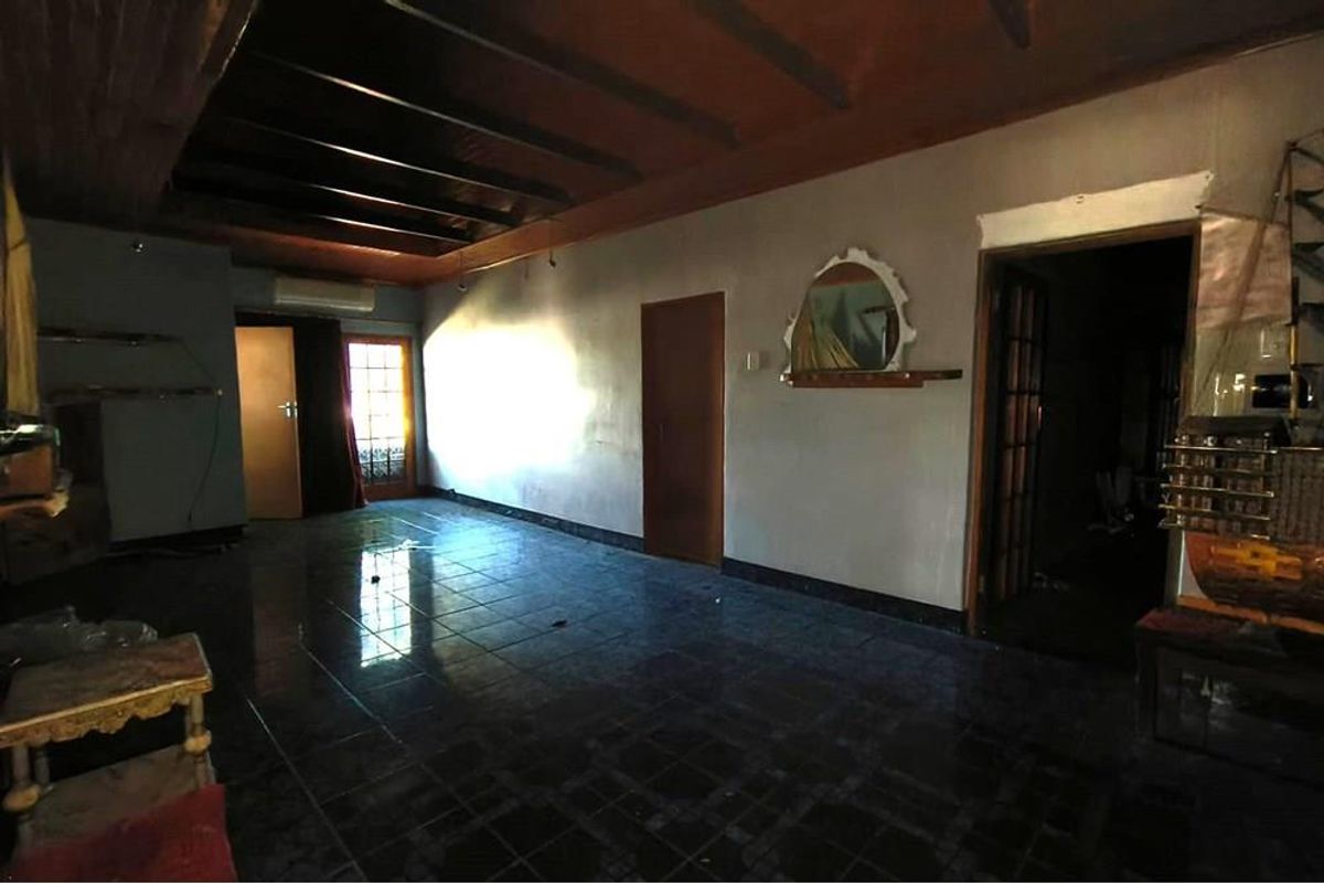 A spacious living area featuring dark tiled flooring, a timber-paneled ceiling, and an integrated air conditioning unit.