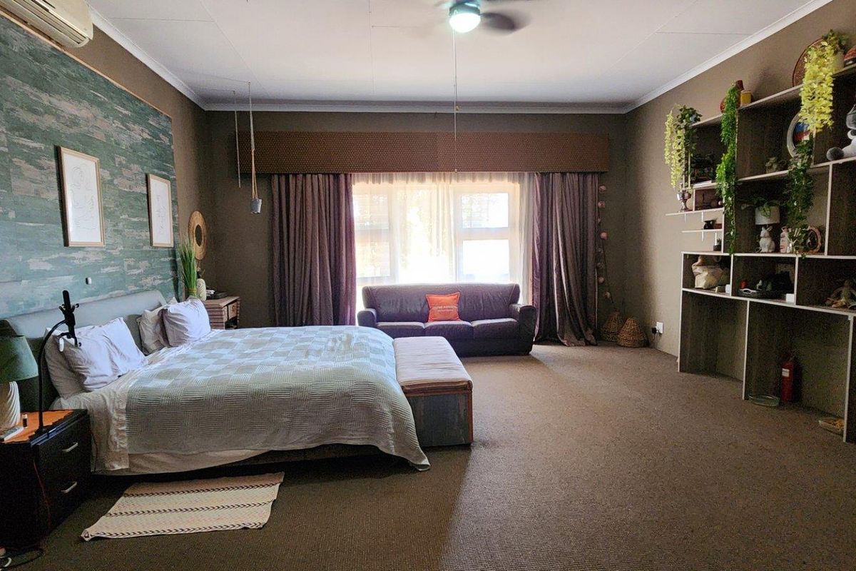 Spacious bedroom featuring a large built-in shelving unit, ceiling fan, and air conditioning unit, offering ample room for furniture and storage.