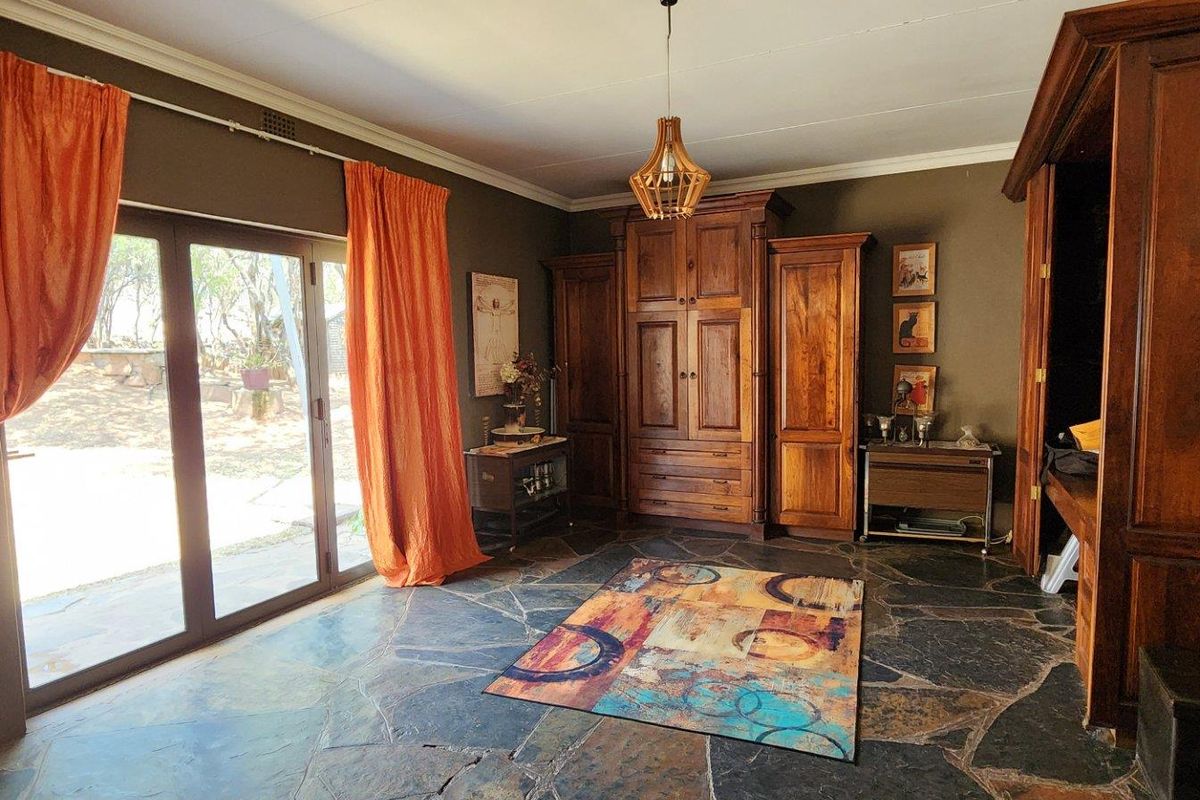 Spacious living room featuring natural slate flooring, built-in wooden cabinetry, and large sliding glass doors providing access to the outdoor area.