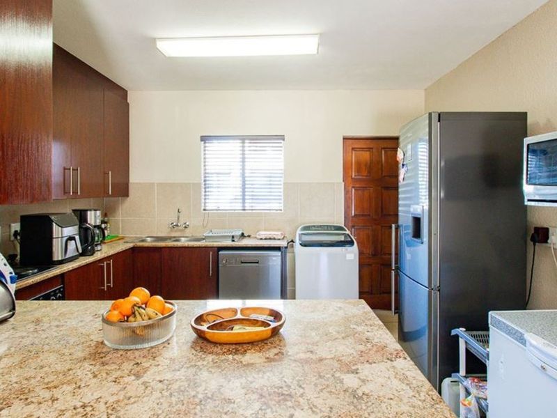 Functional kitchen featuring dark wood cabinetry, granite countertops, tiled backsplash, and integrated microwave space with ample storage and counter area.