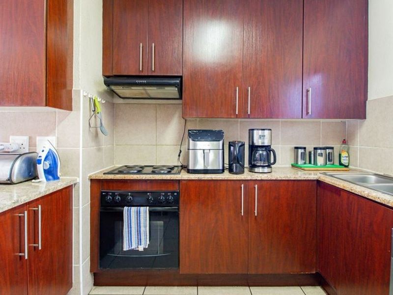 A functional kitchen featuring dark wood cabinetry, granite countertops, a built-in oven with hob, and a tiled backsplash.