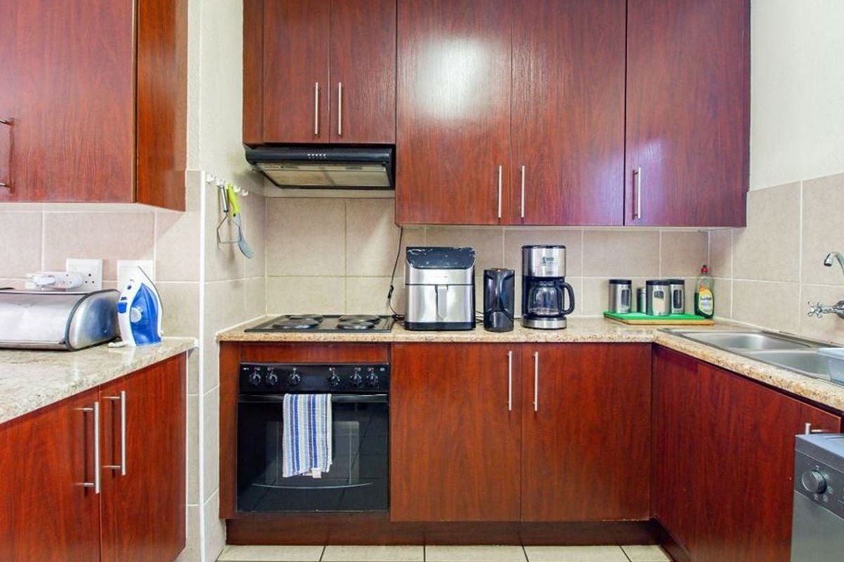 A functional kitchen featuring dark wood cabinetry, granite countertops, a built-in oven with hob, and a tiled backsplash.