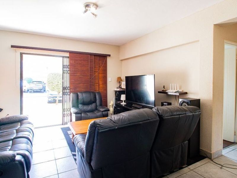 A living room featuring tiled flooring and a sliding glass door with a security gate, providing access to the exterior.