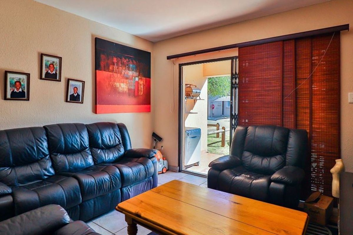 A comfortable living room featuring tiled flooring and a sliding glass door providing direct access to an outdoor patio area.