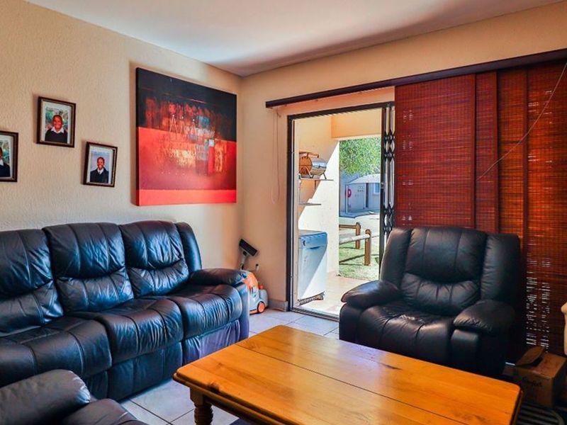 A comfortable living room featuring tiled flooring and a sliding glass door providing direct access to an outdoor patio area.