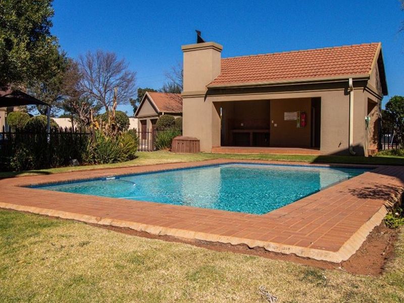 Communal pool area featuring a swimming pool with brick coping and an adjacent covered patio with an outdoor fireplace.