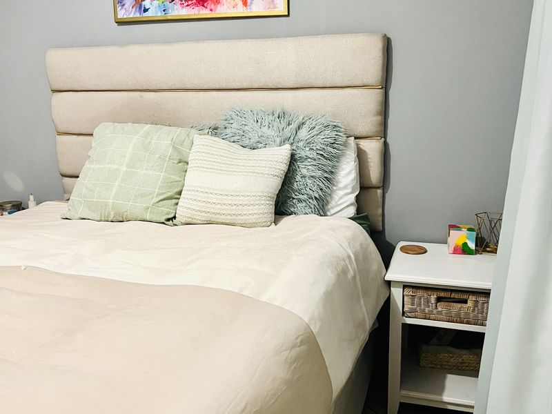 A cozy bedroom featuring neutral wall tones, tiled flooring, and a modern upholstered headboard, creating a comfortable and inviting sleeping space.