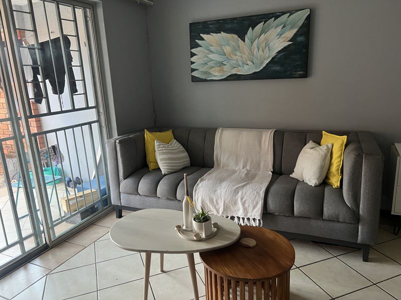 A living room area featuring tiled flooring and a sliding glass door with an integrated security gate leading to an outdoor space.
