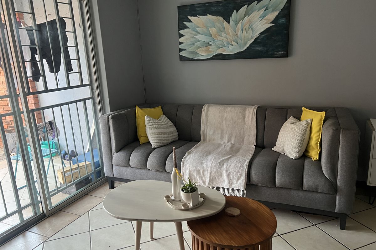 A living room area featuring tiled flooring and a sliding glass door with an integrated security gate leading to an outdoor space.