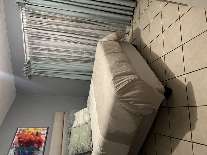A bedroom featuring tiled flooring and a sliding glass door with curtains, providing access to an outdoor area.
