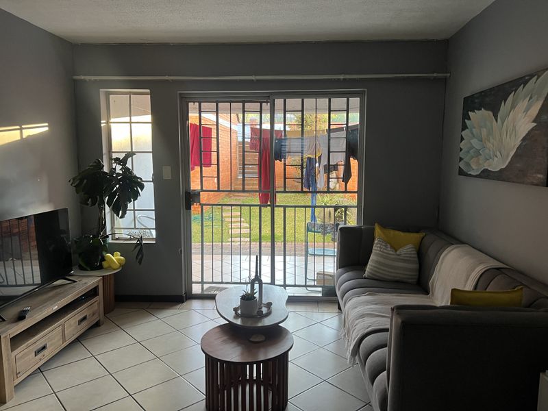 A living room featuring tiled flooring, a sliding glass door with a security gate, and direct access to an outdoor area.