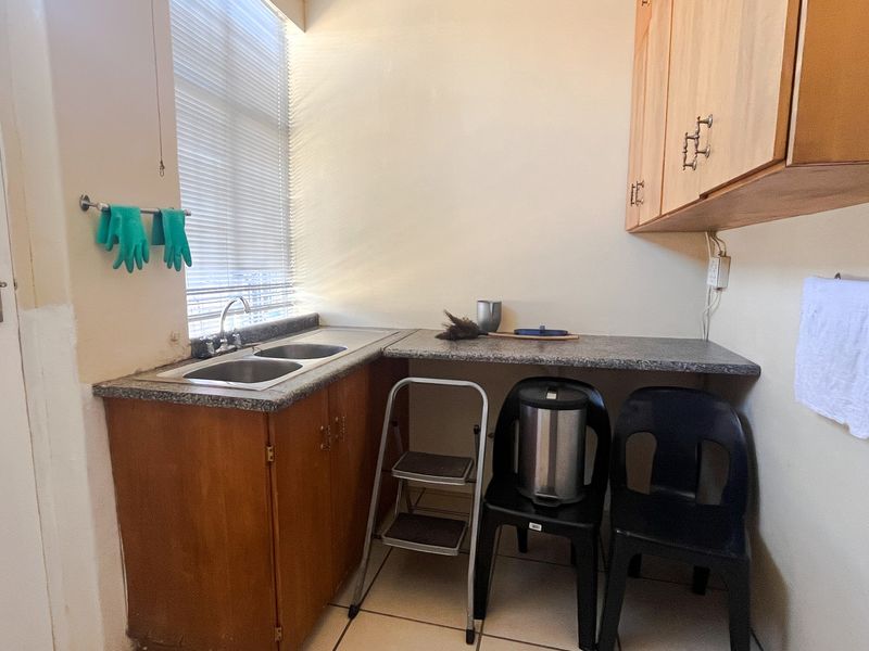 A functional laundry area featuring a double bowl sink, granite countertops, and built-in laminate cabinetry with tiled flooring.