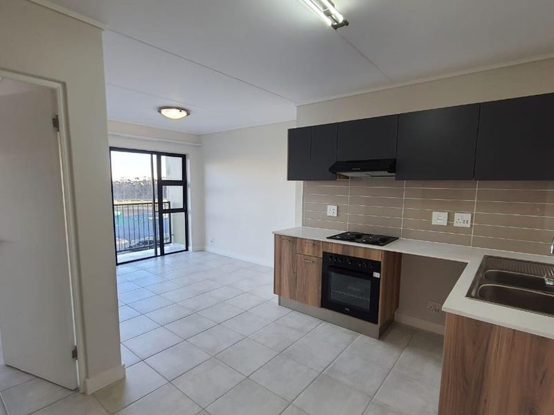 Open-plan kitchen and living area featuring modern cabinetry, built-in oven, hob, and direct access to a private balcony.