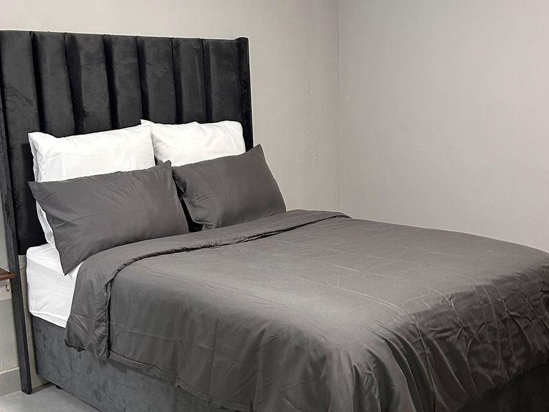 A simple bedroom featuring neutral wall finishes and a functional electrical outlet.