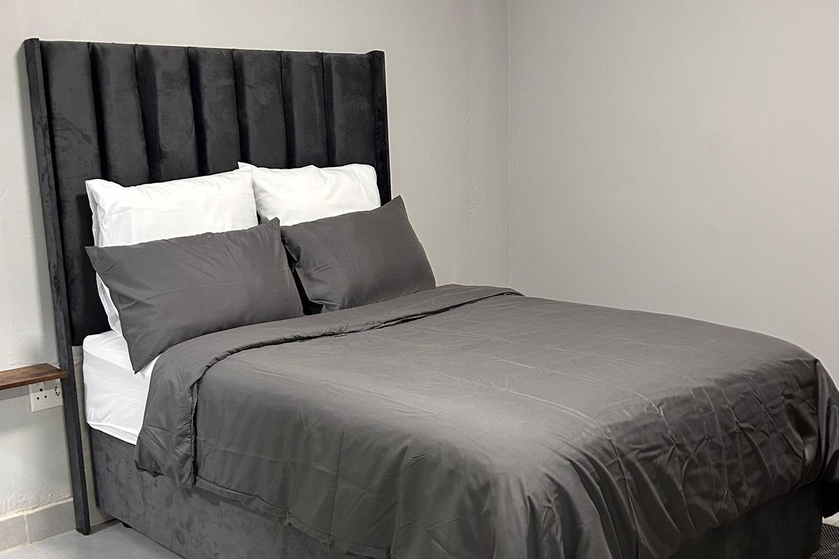 A simple bedroom featuring neutral wall finishes and a functional electrical outlet.