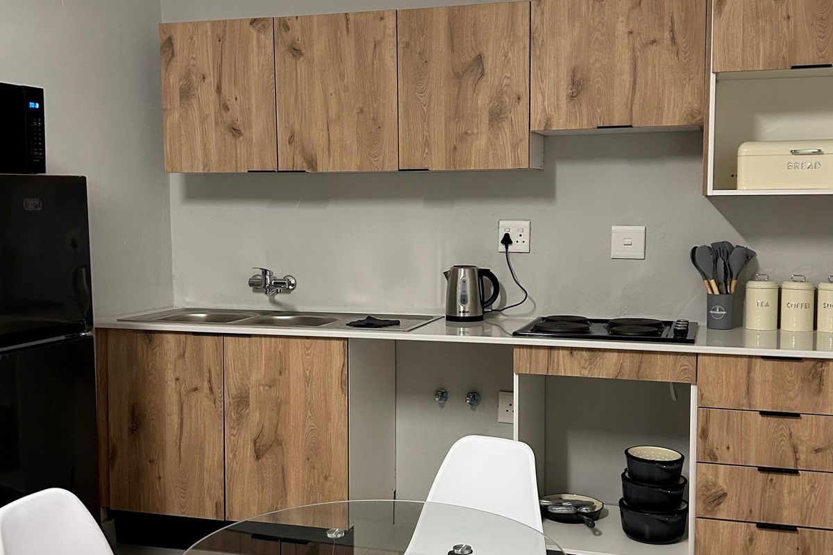 A compact kitchen featuring wood-look cabinetry, a double stainless steel sink, and a built-in electric hob with a clean, modern aesthetic.