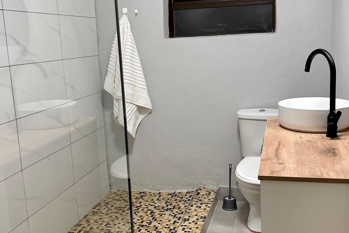Modern bathroom featuring a glass-enclosed shower with mosaic tiling, a contemporary vanity with a vessel basin, and black fixtures.