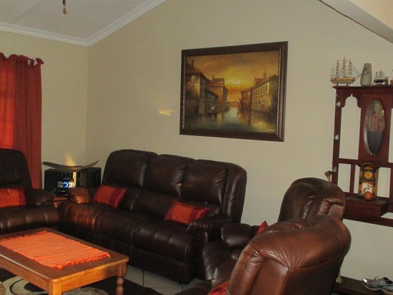 A spacious living room featuring a vaulted ceiling, tiled flooring, and neutral wall finishes, providing a comfortable and well-lit area for relaxation.