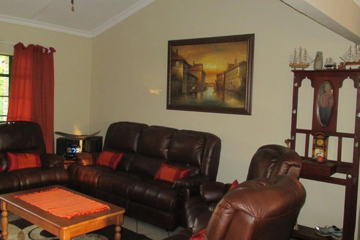 A spacious living room featuring a vaulted ceiling, tiled flooring, and neutral wall finishes, providing a comfortable and well-lit area for relaxation.