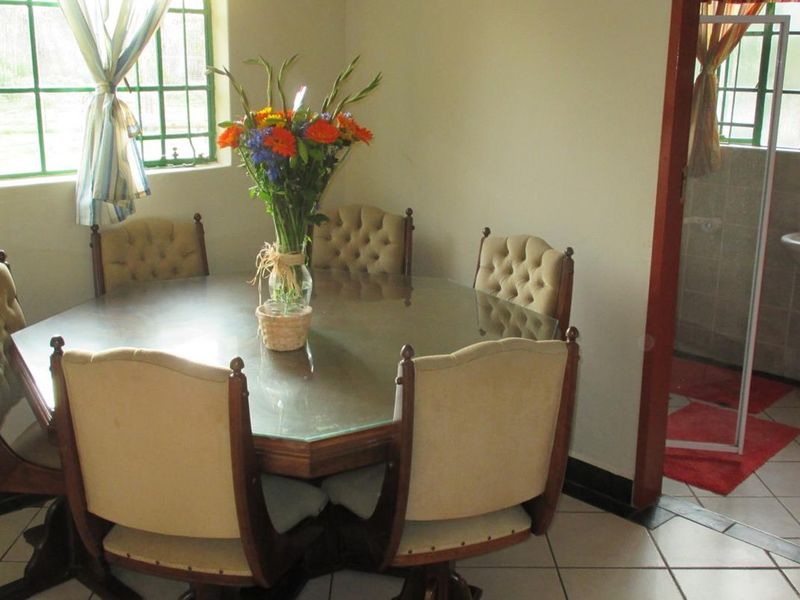Dining area featuring tiled flooring and large windows with security bars, with an adjacent bathroom visible through the doorway.