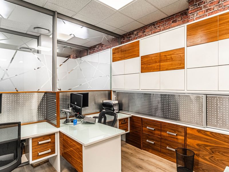 Modern office space featuring custom built-in cabinetry, glass partitions, exposed brick accents, and high-quality finishes throughout.