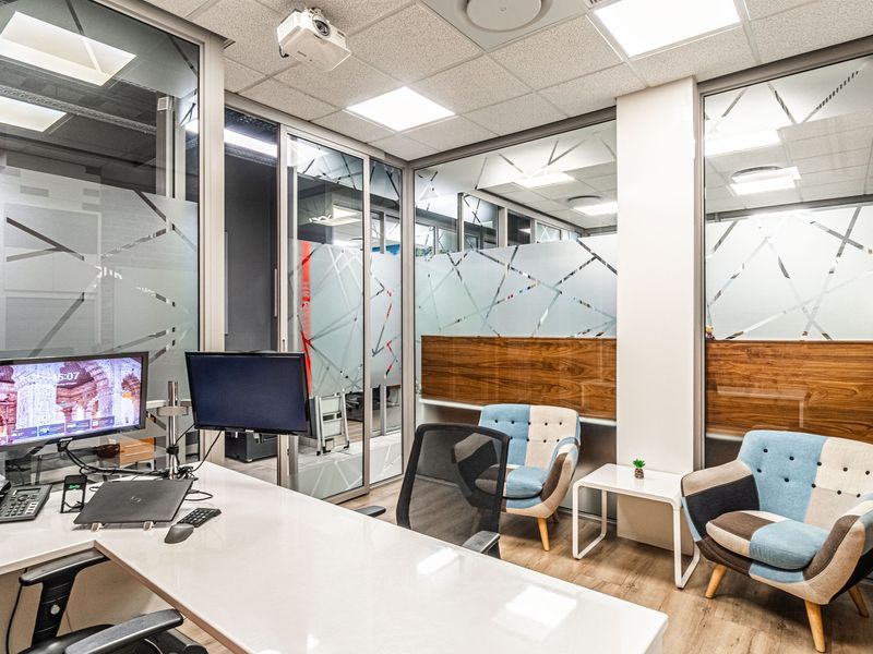 Modern professional office space featuring glass partition walls with decorative privacy film, suspended ceiling, and high-quality laminate flooring.