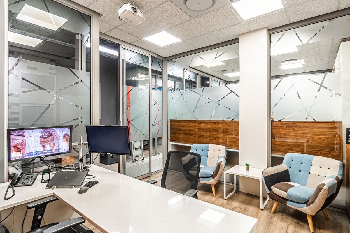 Modern professional office space featuring glass partition walls with decorative privacy film, suspended ceiling, and high-quality laminate flooring.