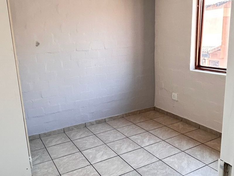An empty bedroom featuring tiled flooring and painted brick walls, providing a blank canvas for personalization.