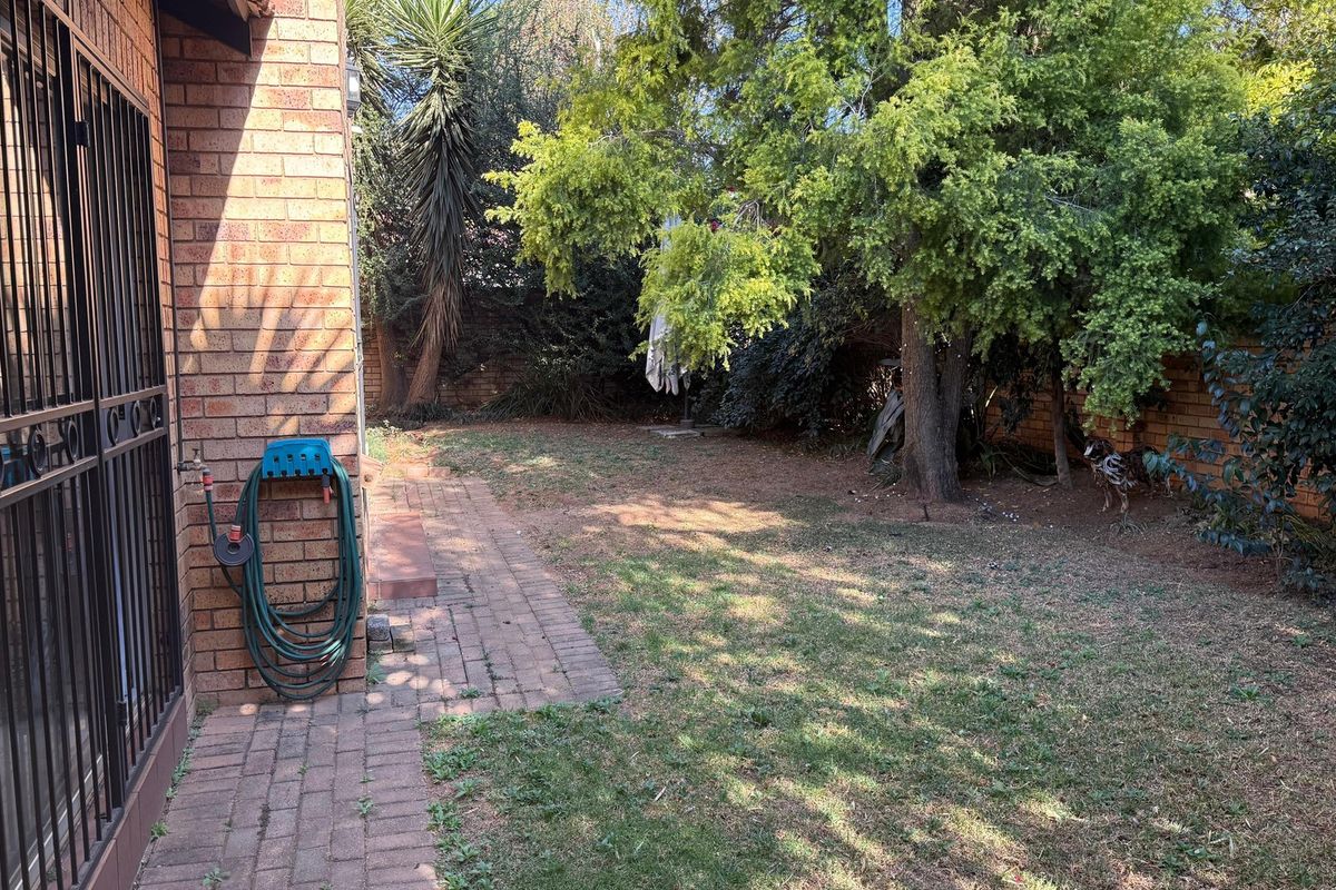 A private rear garden featuring brick paving, established trees, and a brick boundary wall, offering potential for landscaping and outdoor living improvements.