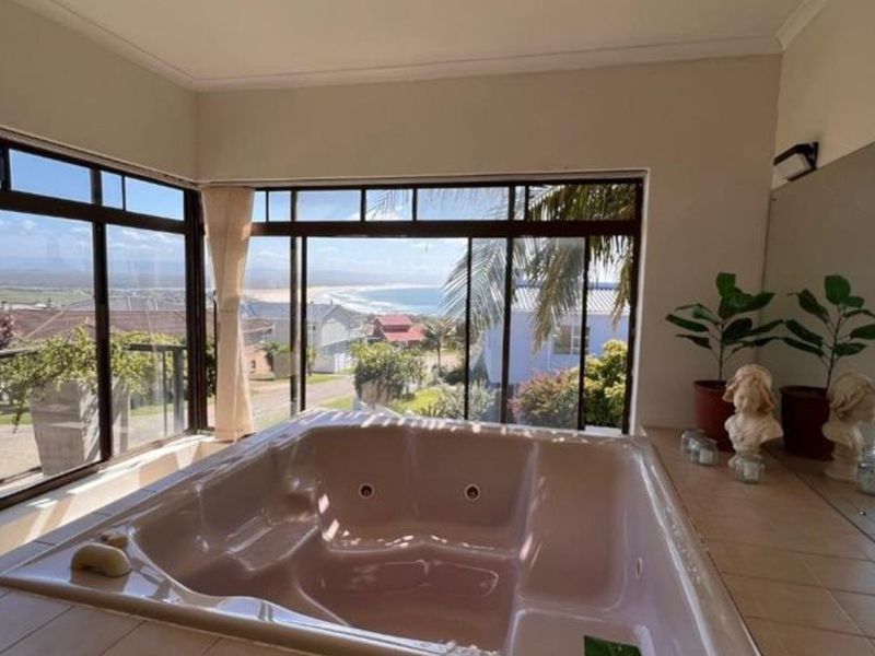 Bathroom featuring a built-in spa bath with expansive windows offering panoramic coastal views and natural light.