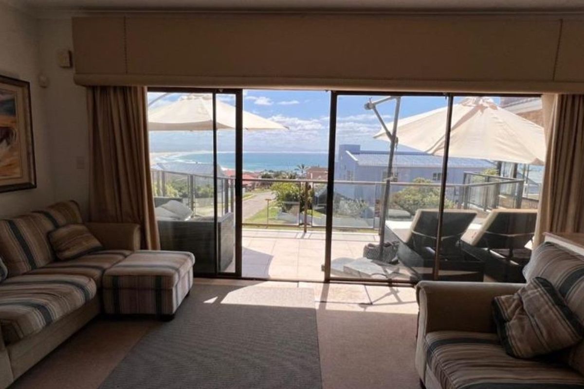 Living room featuring large sliding glass doors that open onto a balcony with scenic ocean views.