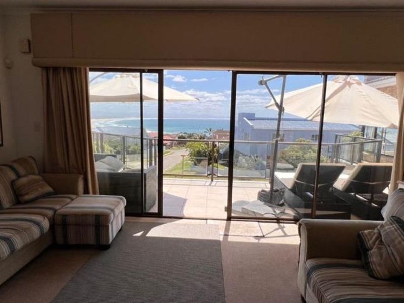 Living room featuring large sliding glass doors that open onto a balcony with scenic ocean views.