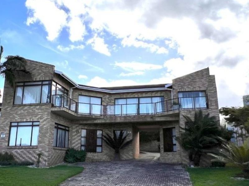 A two-story face-brick residential property featuring a paved driveway, covered entrance, and an upper-level balcony with metal railings.