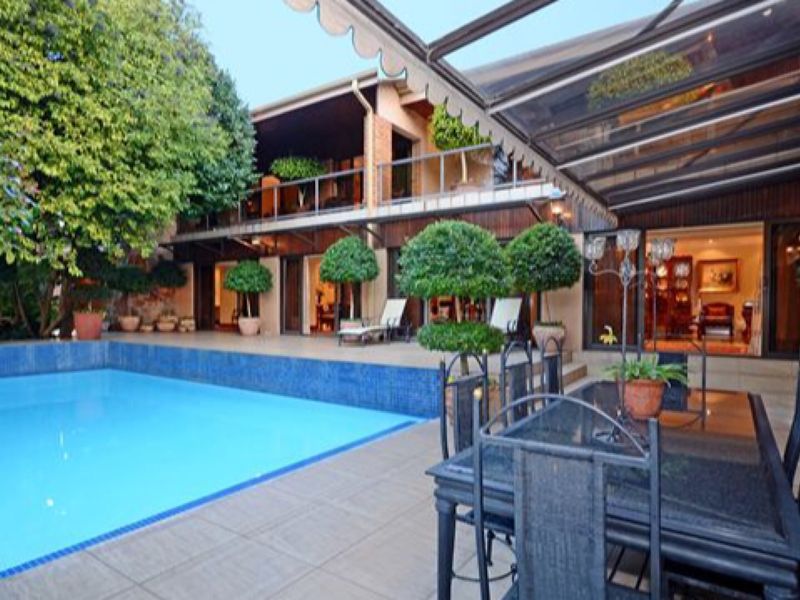 Spacious outdoor pool area featuring a tiled patio, retractable awning, and direct access to the residence through large sliding glass doors.