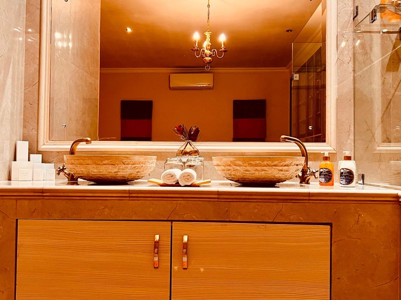 Elegant bathroom featuring a double vanity with stone vessel sinks, marble countertop, large mirror, and a glass-enclosed shower area.