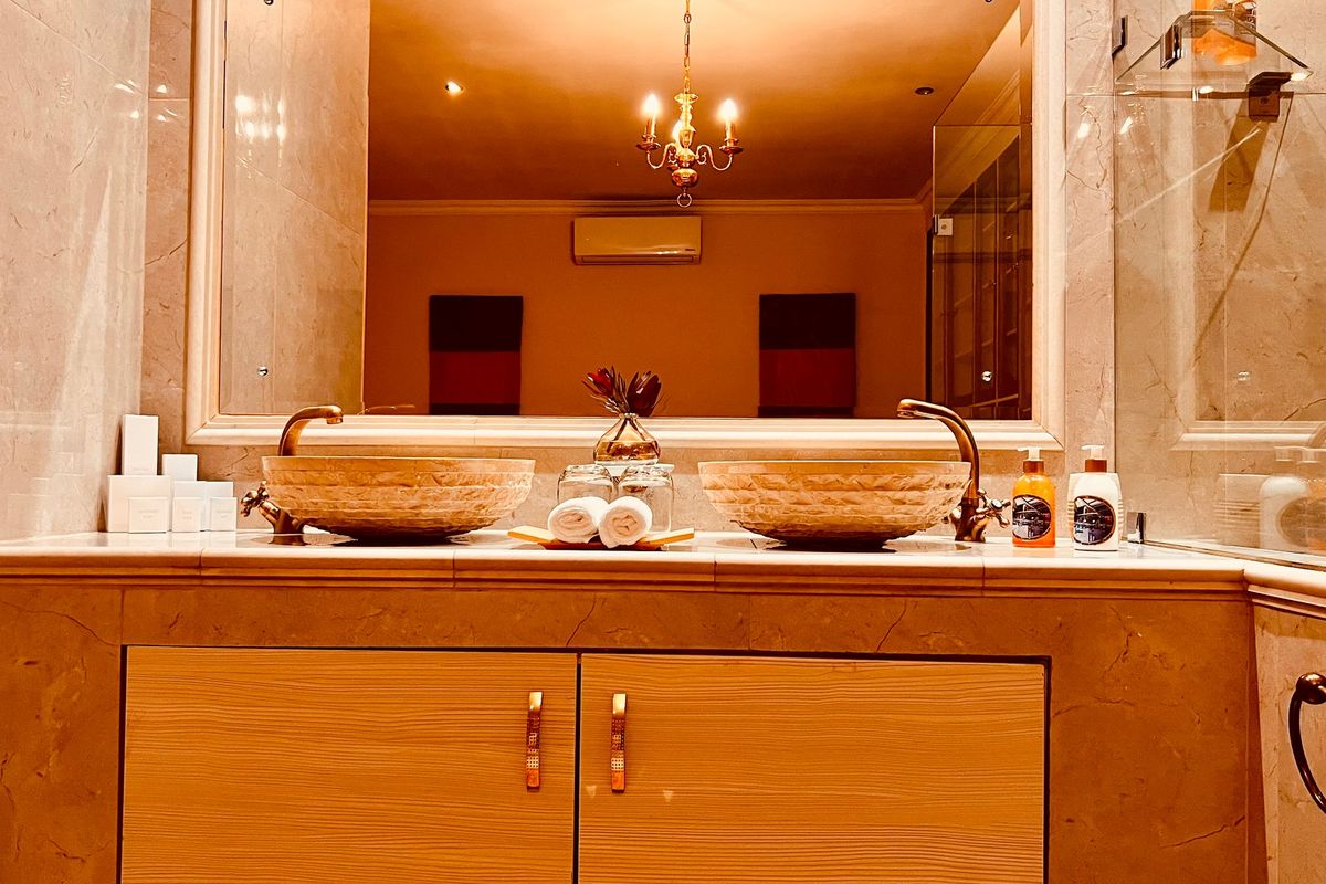 Elegant bathroom featuring a double vanity with stone vessel sinks, marble countertop, large mirror, and a glass-enclosed shower area.