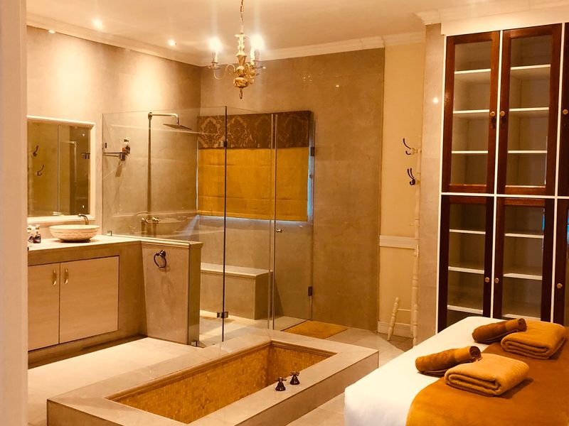 A spacious, well-appointed bathroom featuring a sunken bathtub, a separate glass-enclosed shower, a vessel sink vanity, and extensive built-in storage cabinetry.