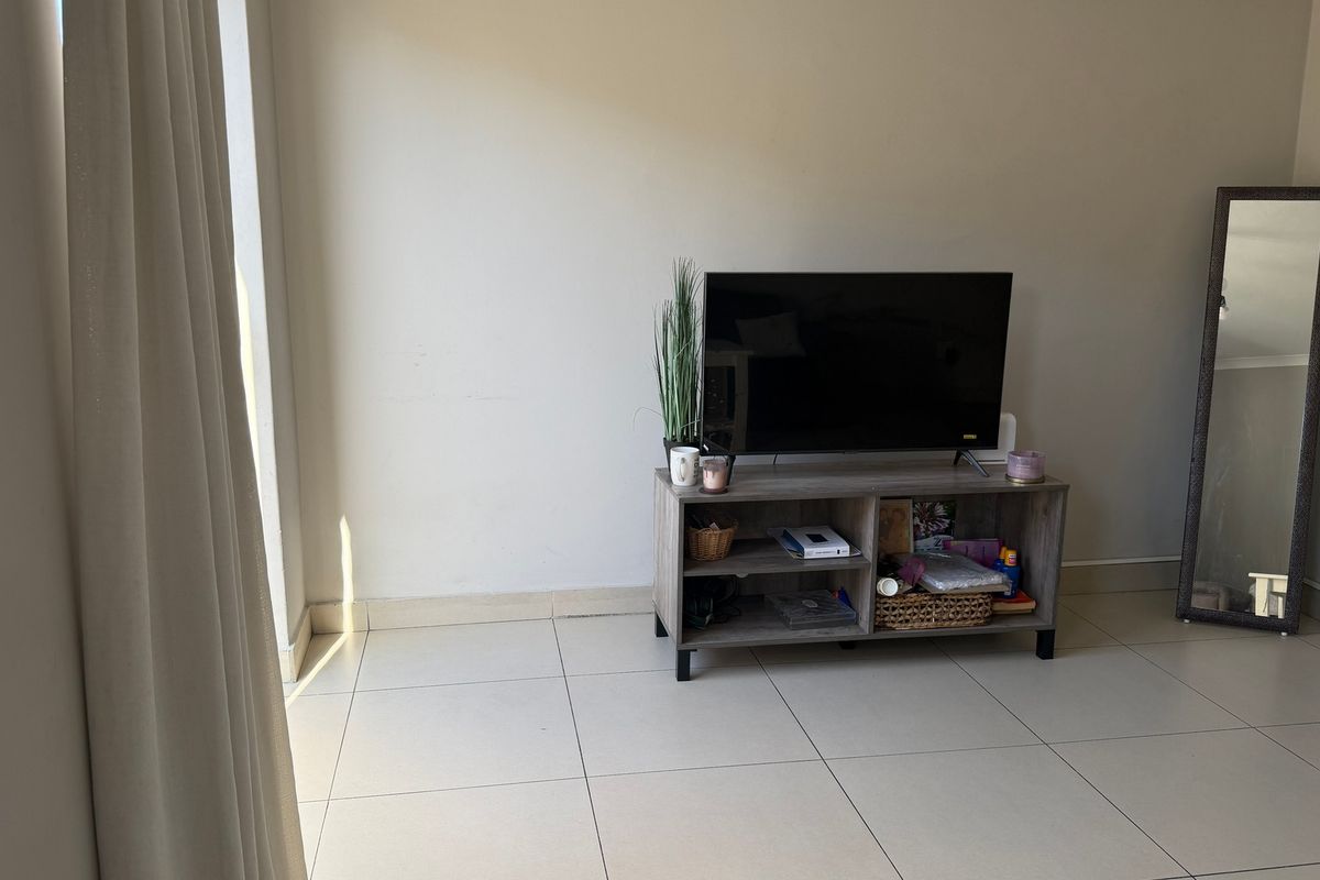 A living area featuring neutral tiled flooring and plain walls, providing a simple and functional space ready for personalization.