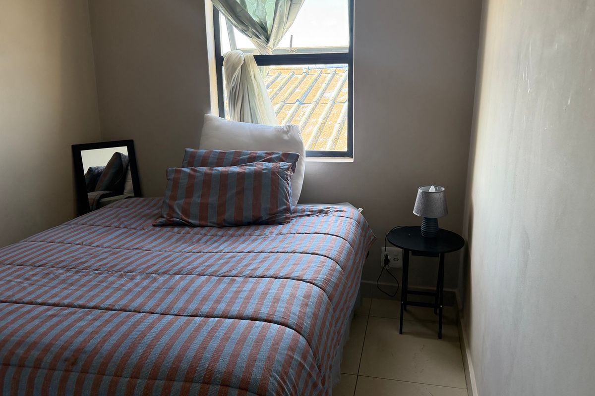 A compact bedroom featuring tiled flooring and a window providing natural light.