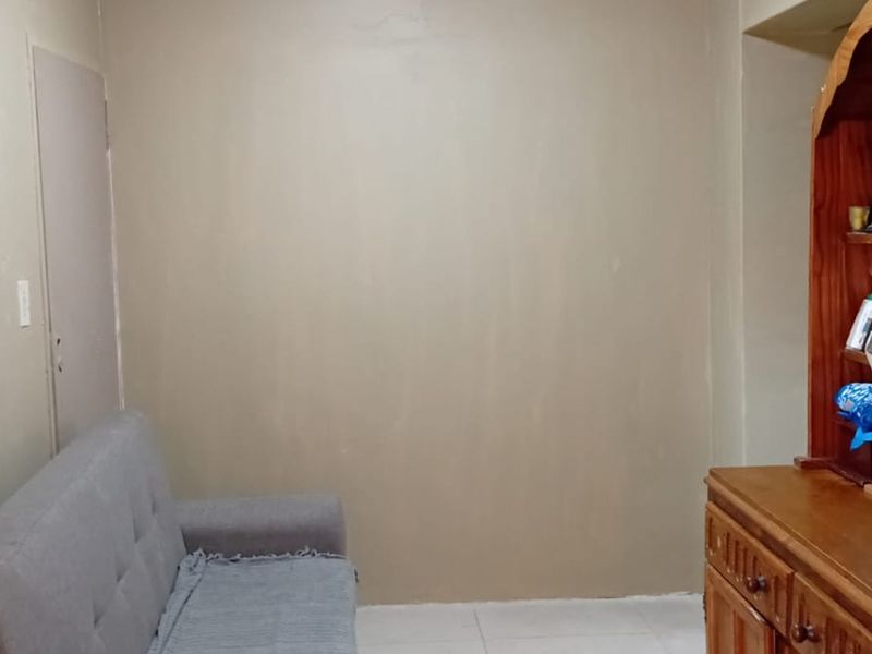 A small living area featuring neutral wall tones and tiled flooring, offering a blank canvas for potential interior updates and modernization.