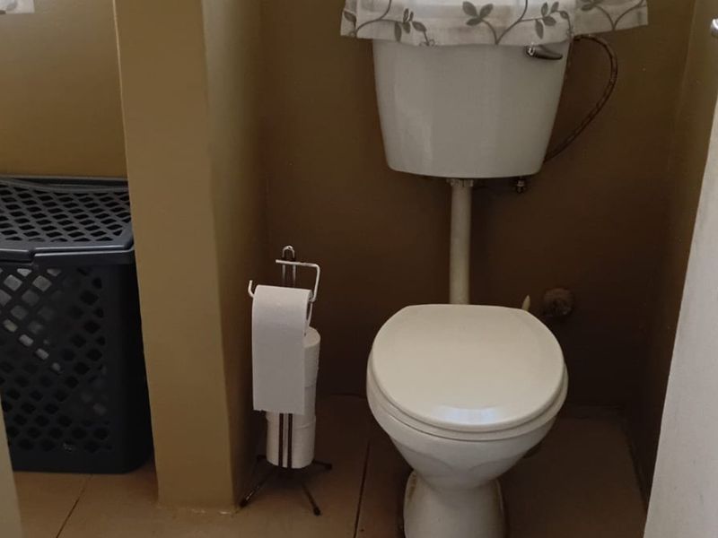 A compact bathroom featuring a standard white toilet and cistern, finished with neutral wall paint.