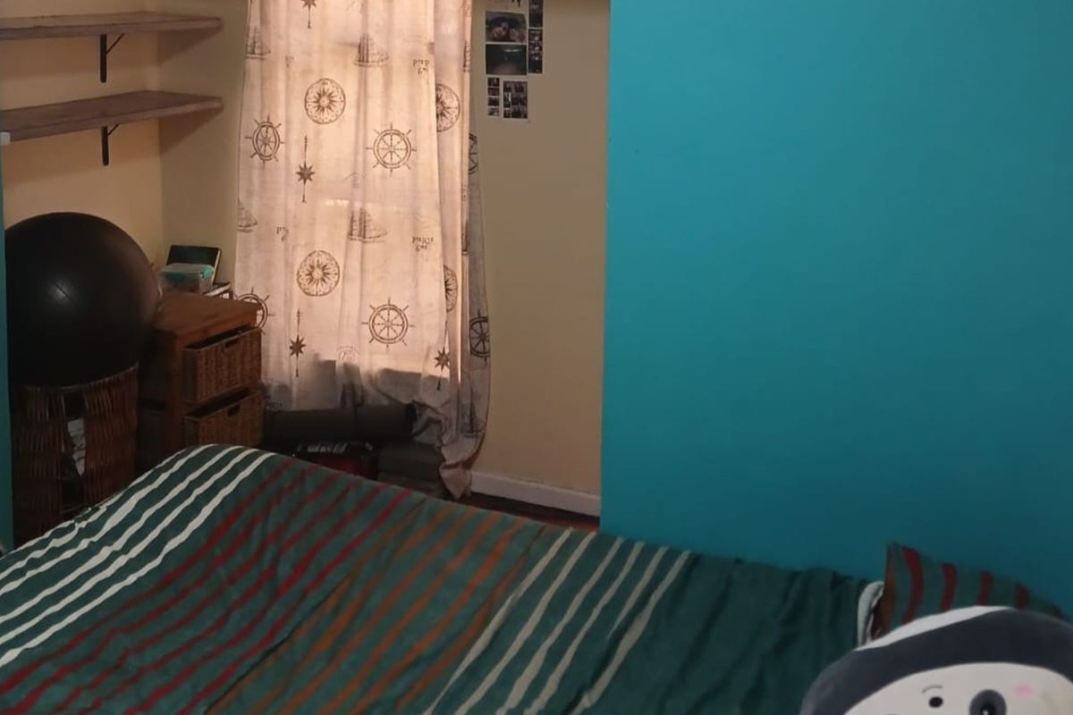 A bedroom featuring built-in shelving and a window with a curtain.
