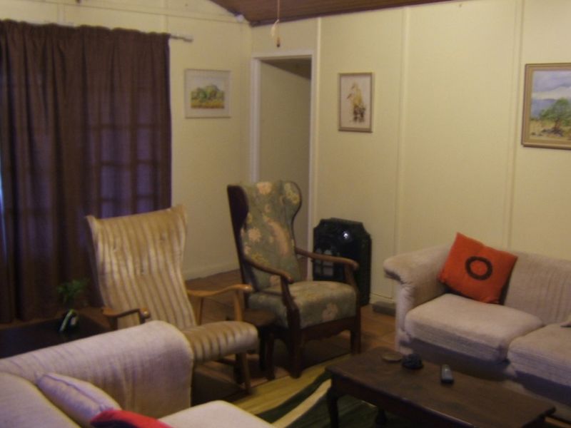 A living room featuring panelled walls and a timber-look ceiling, with a sliding glass door providing access to the exterior.