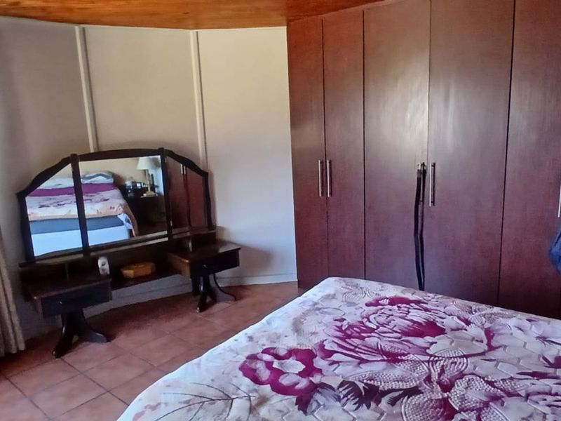 A bedroom featuring built-in wooden cupboards, tiled flooring, and a wooden ceiling, offering a functional space with traditional finishes.